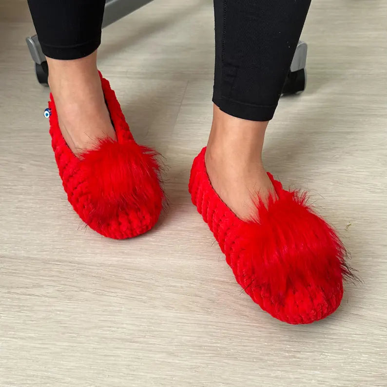 Red fluffy slippers worn indoors on a light wooden floor.